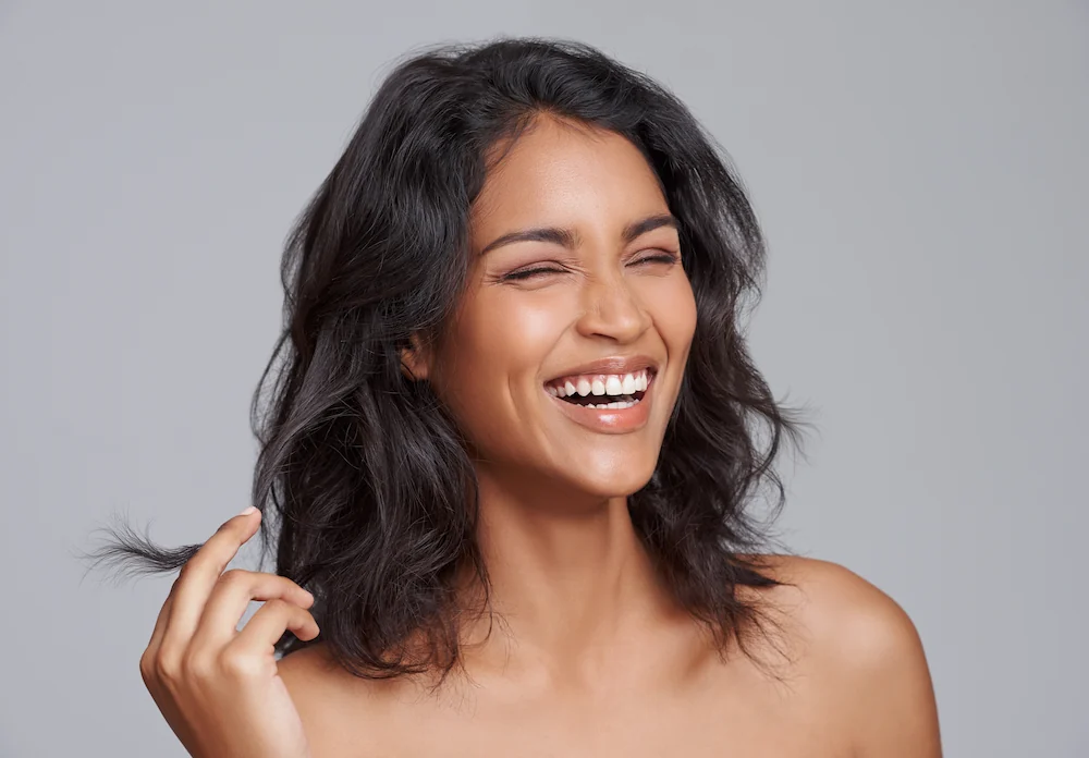 Brown woman with glowing skin smiling and laughing