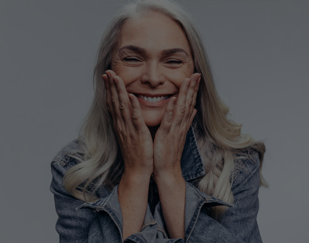 Older woman smiling with hands on her face